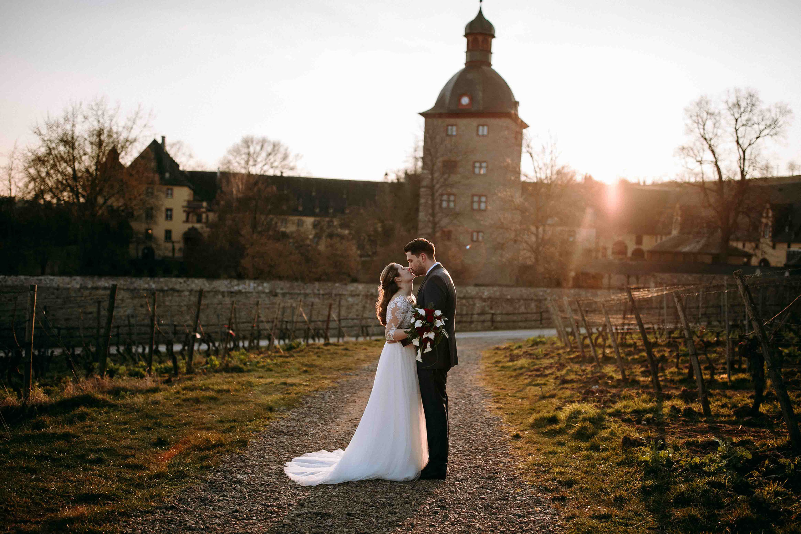 Brautpaar küsst sich im Sonnenuntergang vor Schloss Vollrads – perfekte Hochzeitslocation im Rheingau.