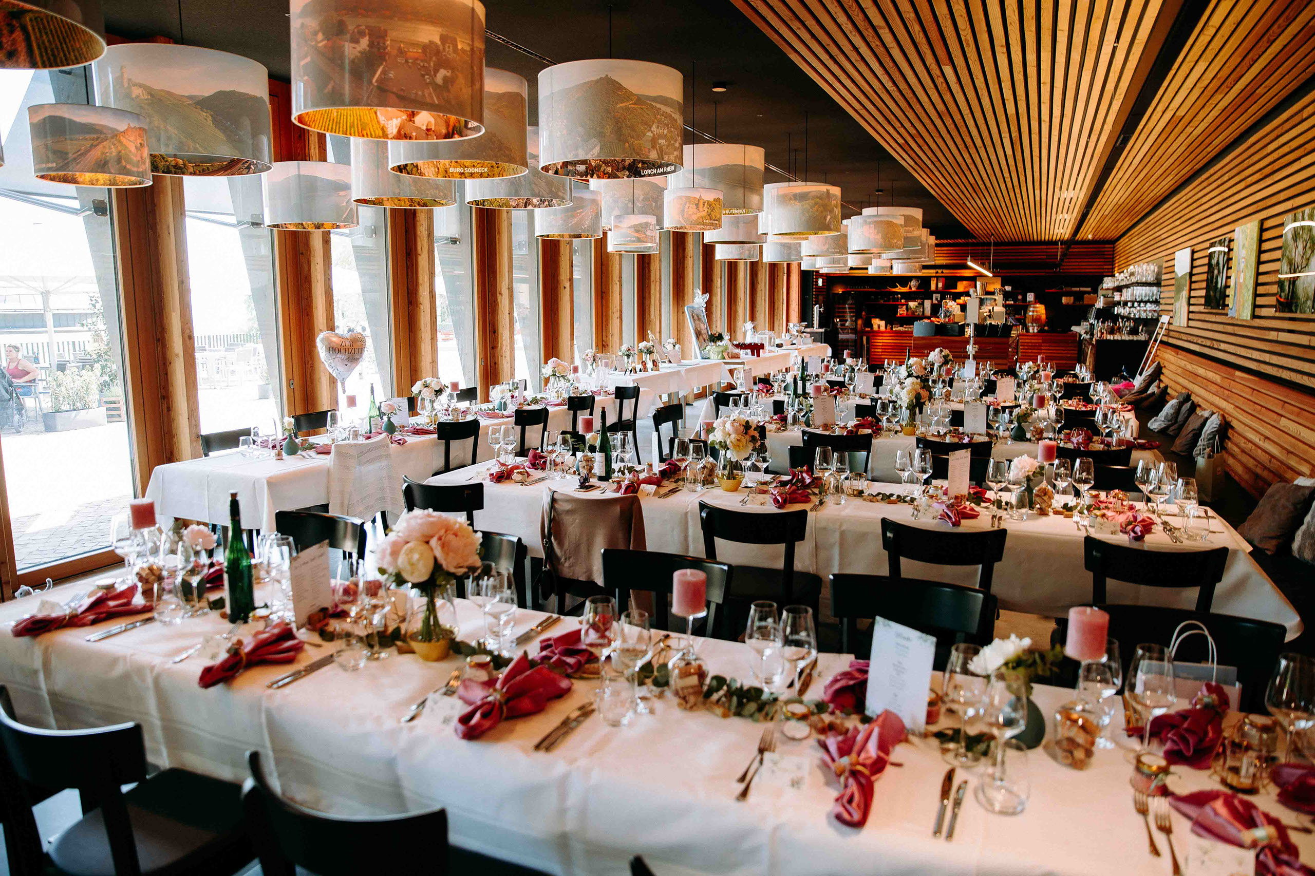 Hochzeitsdinner im festlich dekorierten Innenraum der Location "Am Niederwald" mit Blick ins Grüne.