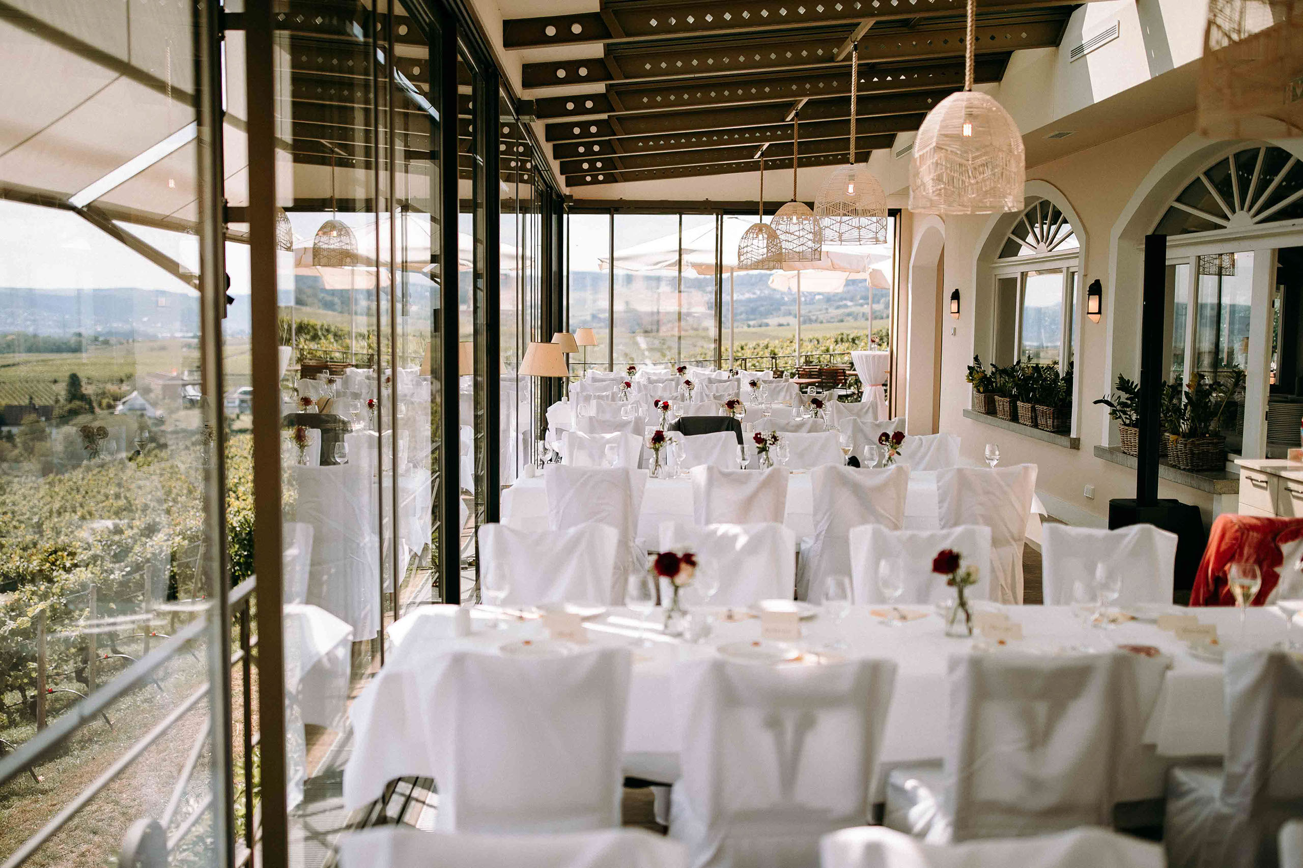 Elegante Hochzeitslocation Schloss Johannisberg mit weiß gedeckten Tischen im Wintergarten und Blick auf die Weinberge