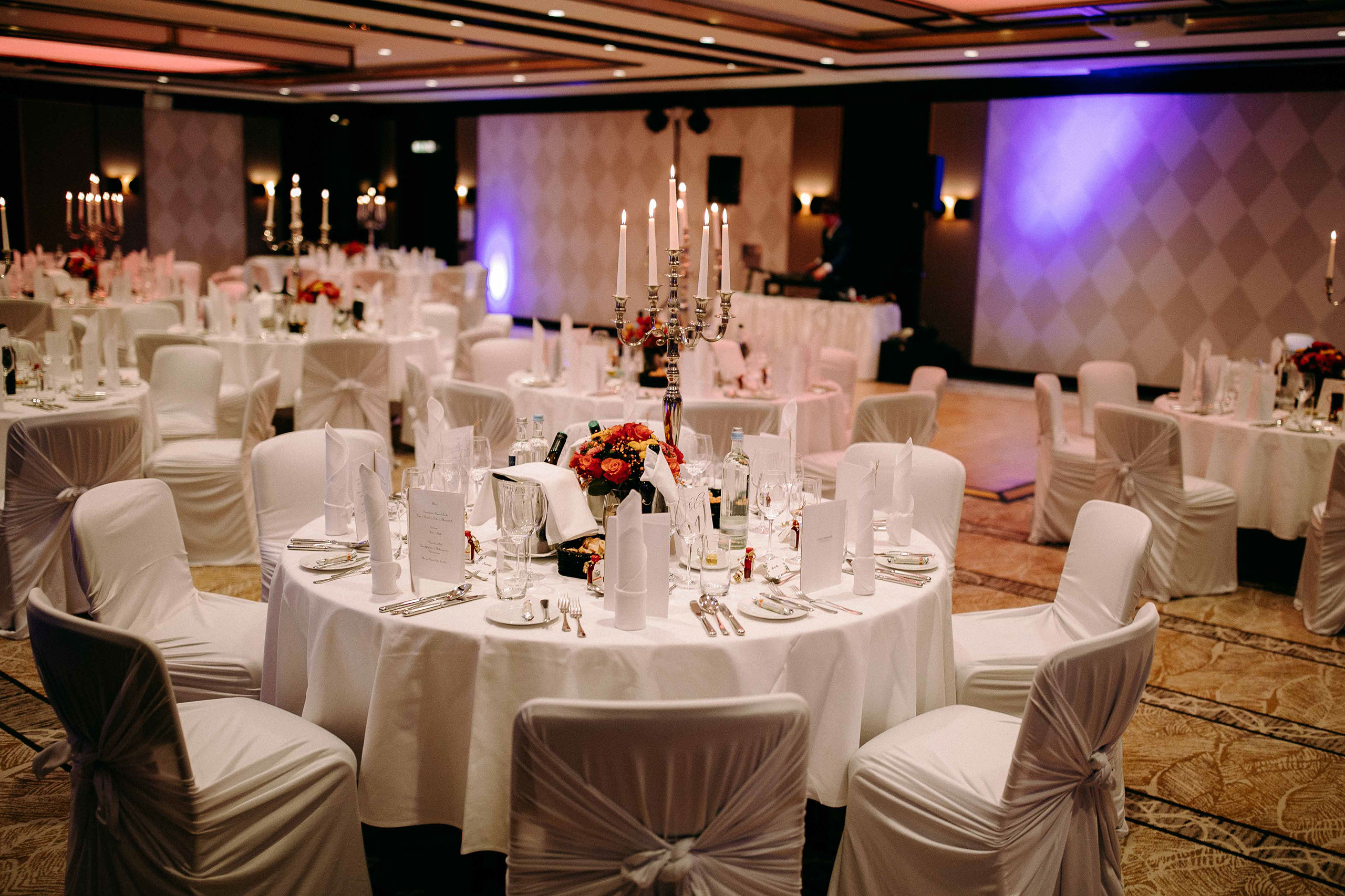 Feierlich gedeckter Hochzeitssaal mit weißen Hussen und Floristik im Steigenberger Hotel – Hochzeitsfotograf Bad Homburg