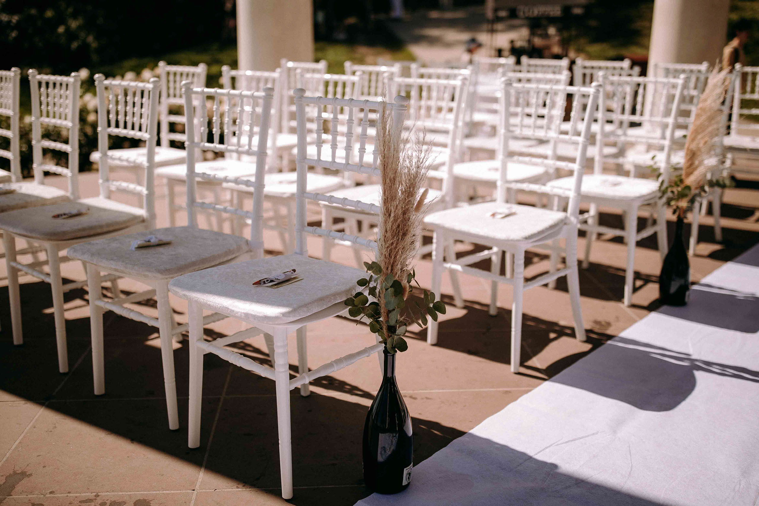 Detailansicht der weißen Stühle mit dekorativen Elementen im Niederwaldtempel zur Hochzeit.