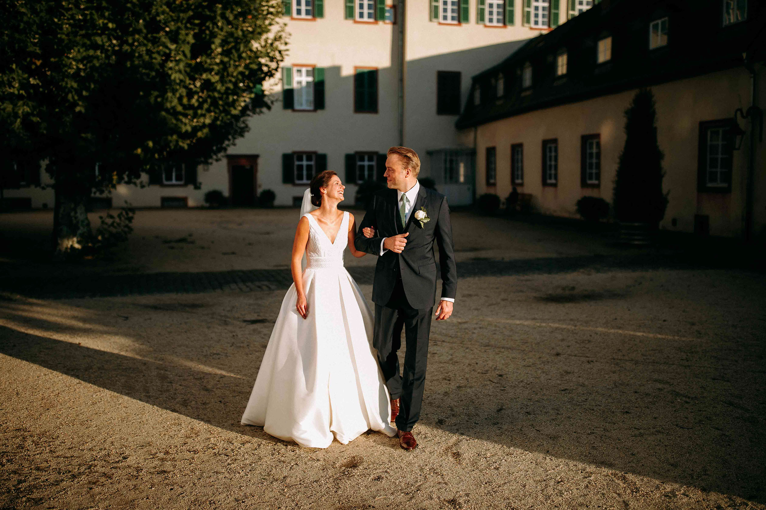 Hochzeitslocation Schloss Bad Homburg: Paarspaziergang im festlichen Innenhof vom weissen Turm in der Abendsonne.