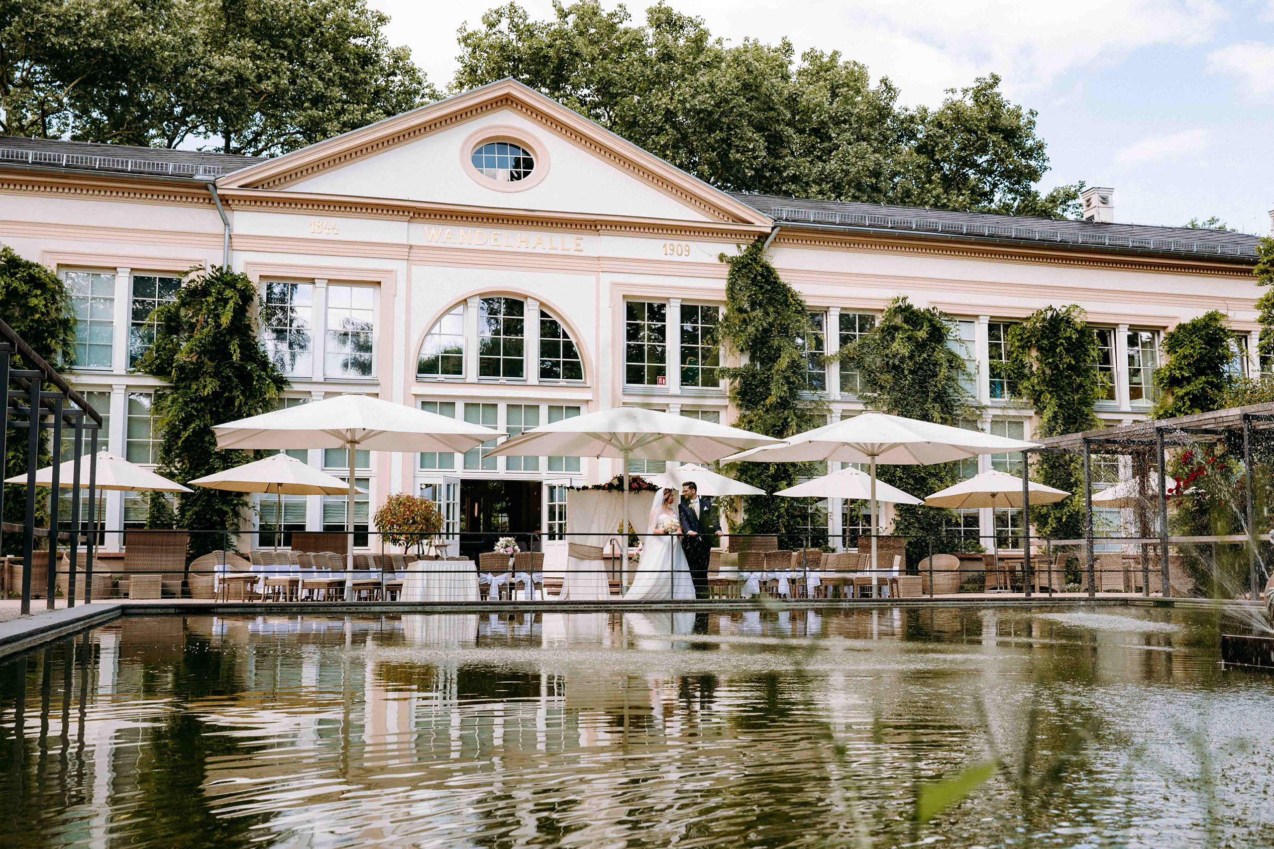 Wandelhalle von außen mit Brautpaar und See im Vordergrund