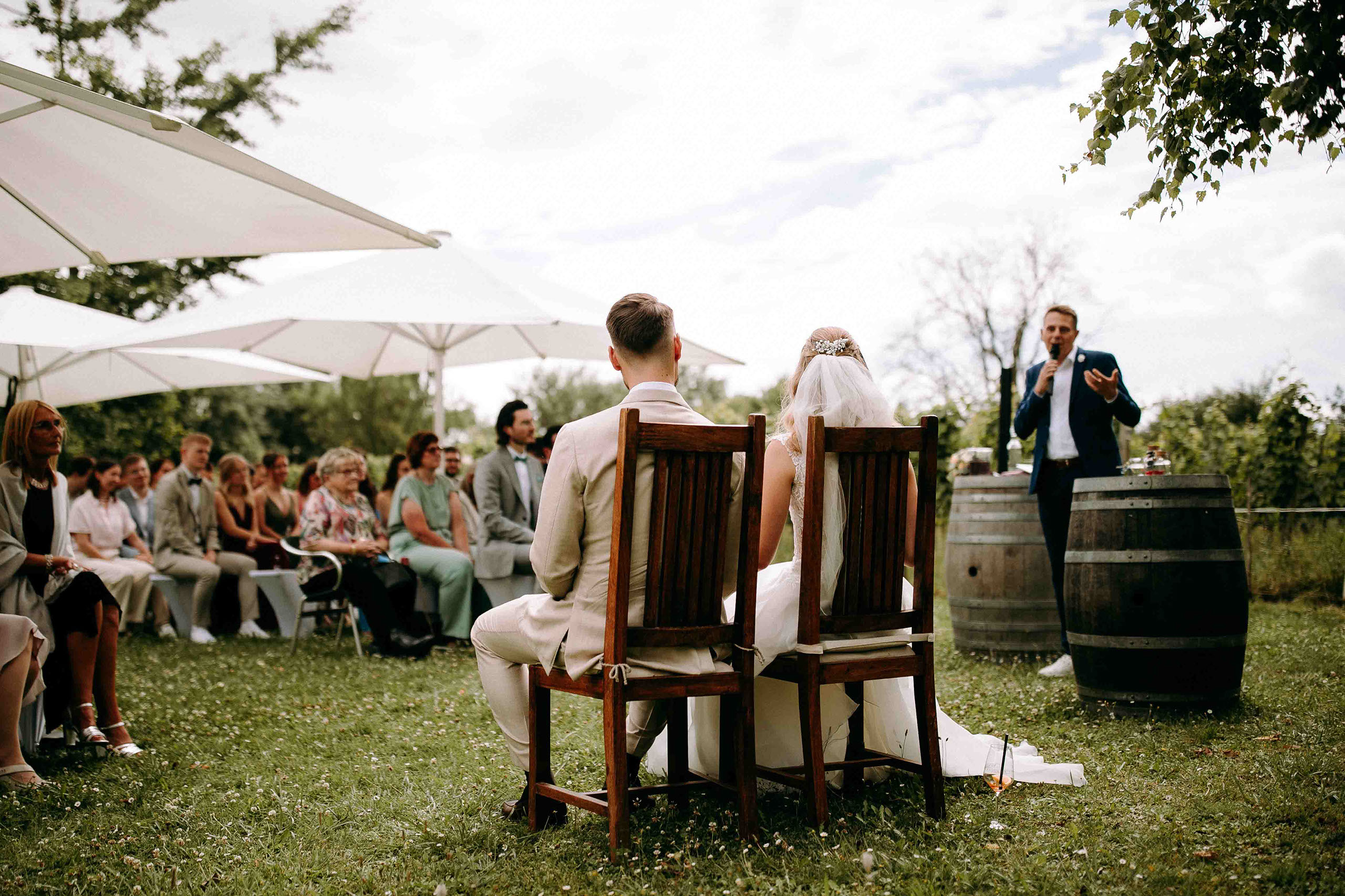 Redner hält emotionale Hochzeitsrede vor dem Brautpaar auf dem Rasen des Draiser Hofs