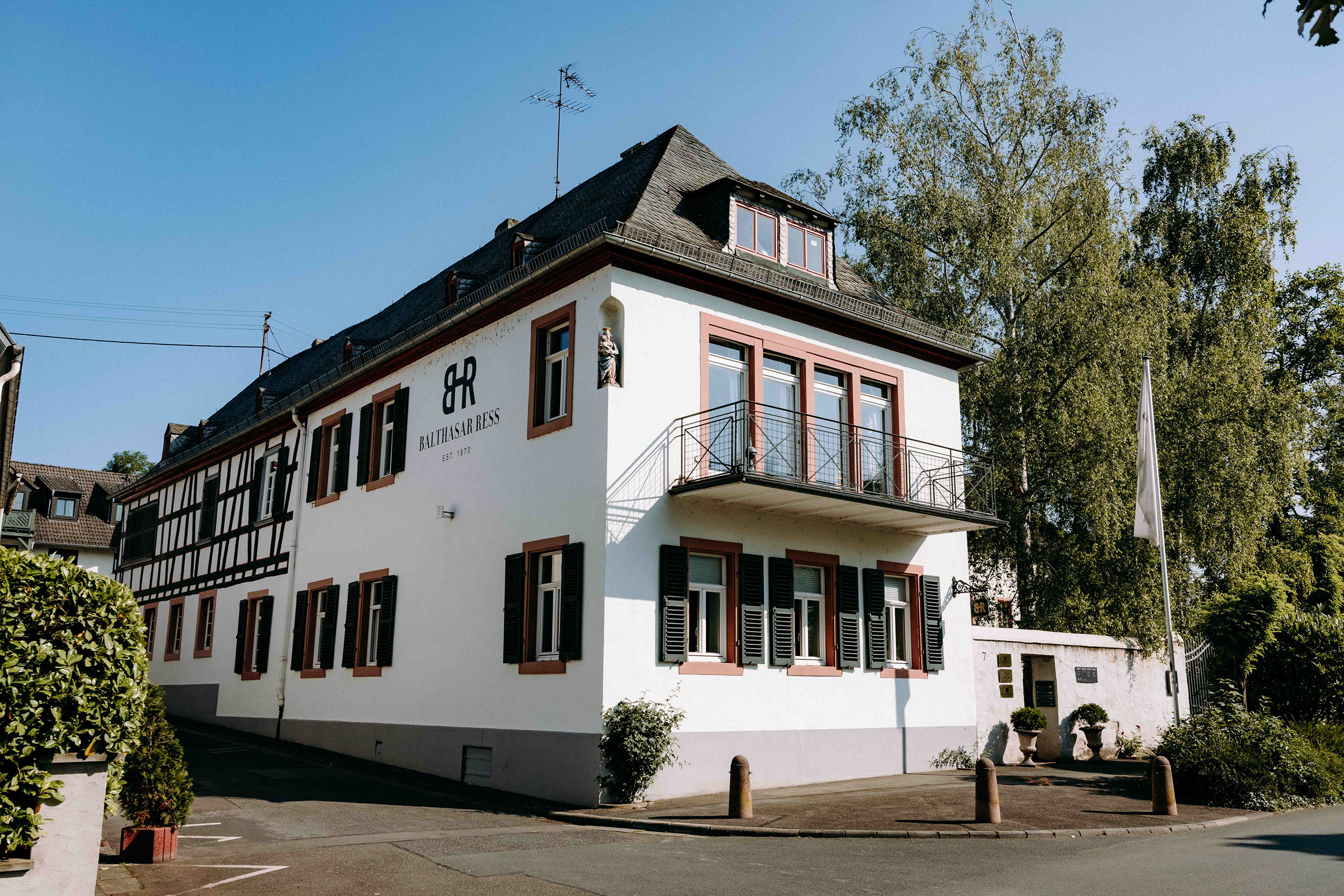 Frontansicht des Weinguts Balthasar Ress mit Fachwerk und weißen Fassaden – traditionsreiche Hochzeitslocation für elegante Feiern, fotografiert