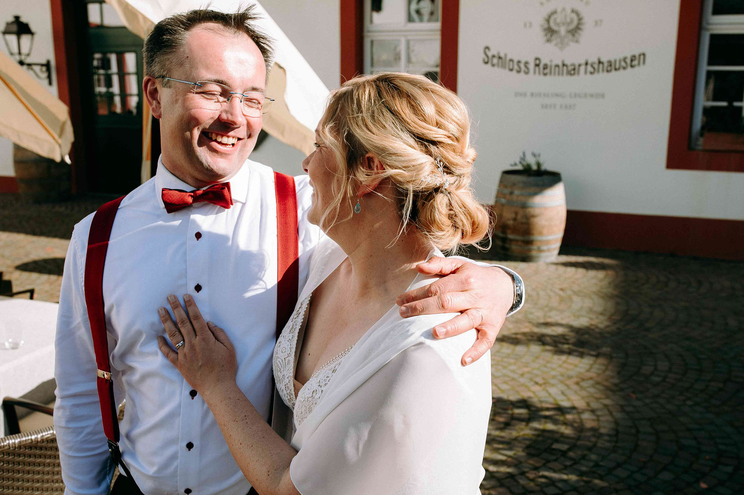 Braut und Bräutigam lachen herzlich vor der Fassade von Schloss Reinhartshausen – authentische Hochzeitsfotos Rheingau