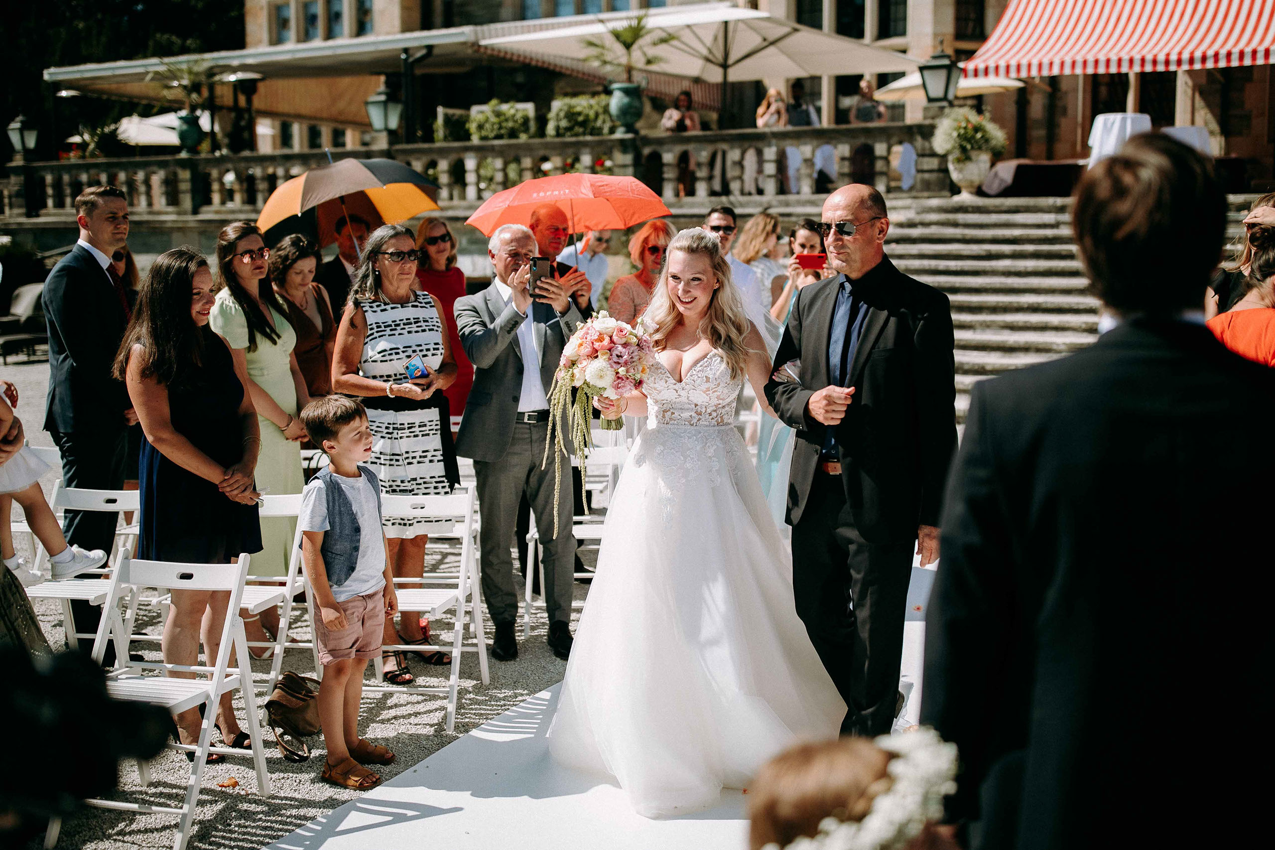 Die Braut beim Einzug zur freien Trauung im Schlosshotel Kronberg mit Blumenschmuck und Hochzeitsgästen.