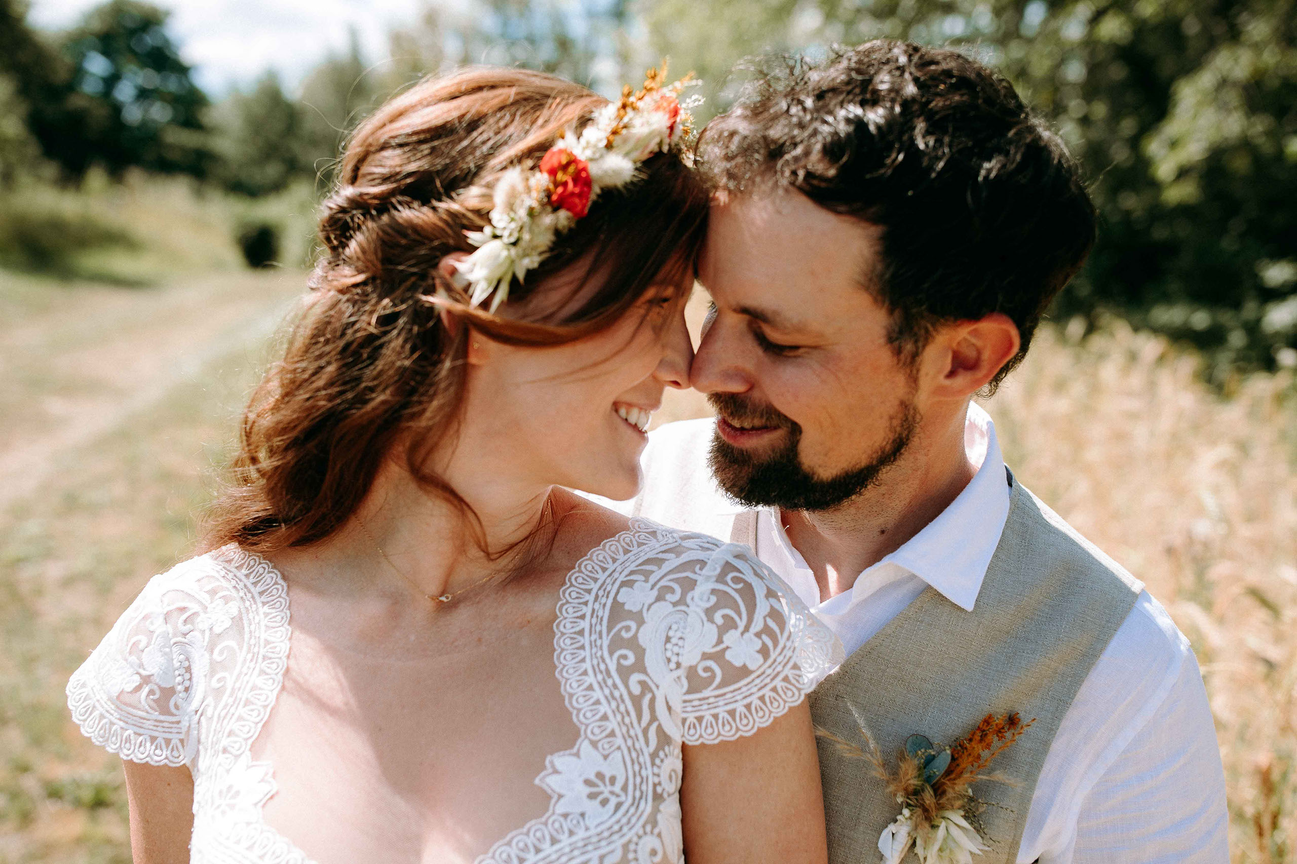 Braut und Bräutigam stehen Stirn an Stirn und lächeln sich liebevoll an.