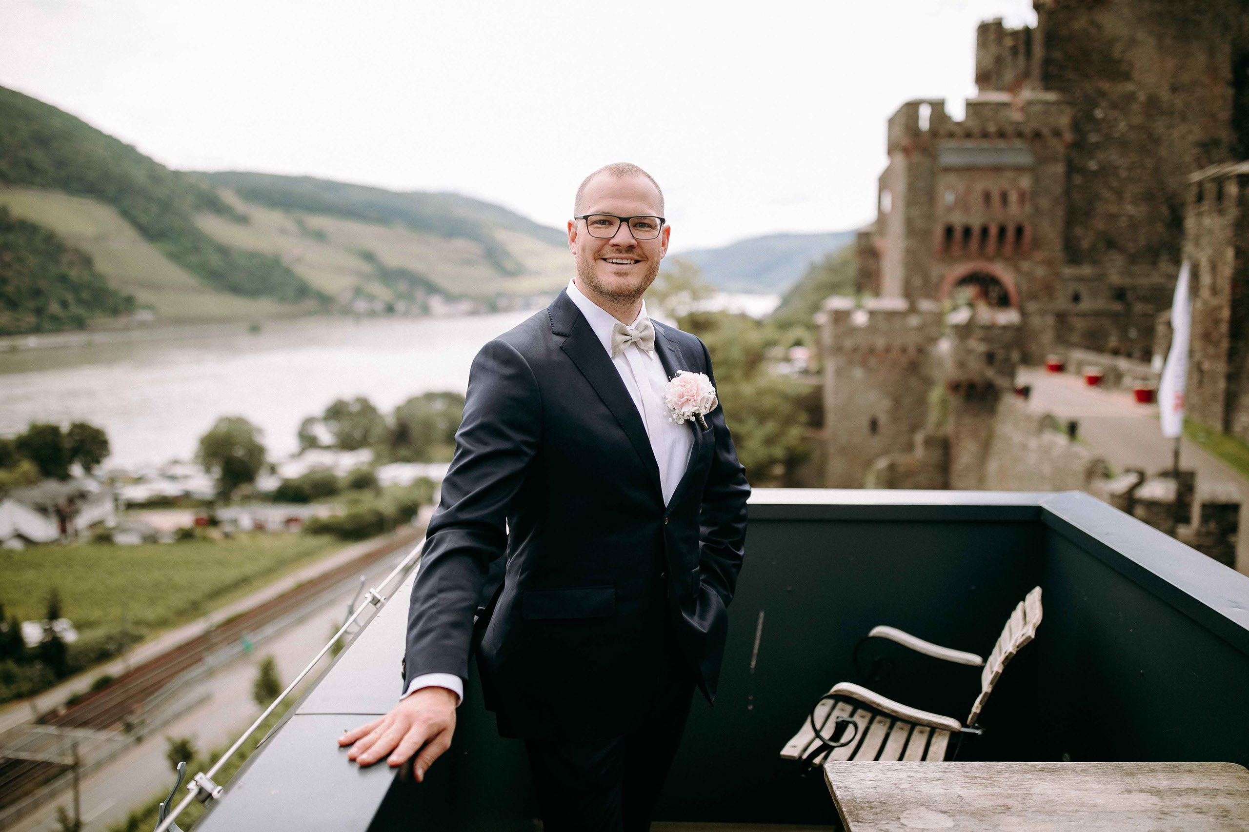 Bräutigam im eleganten Anzug mit Rheinblick vor Burg Reichenstein – Hochzeitsfotograf Rheingau