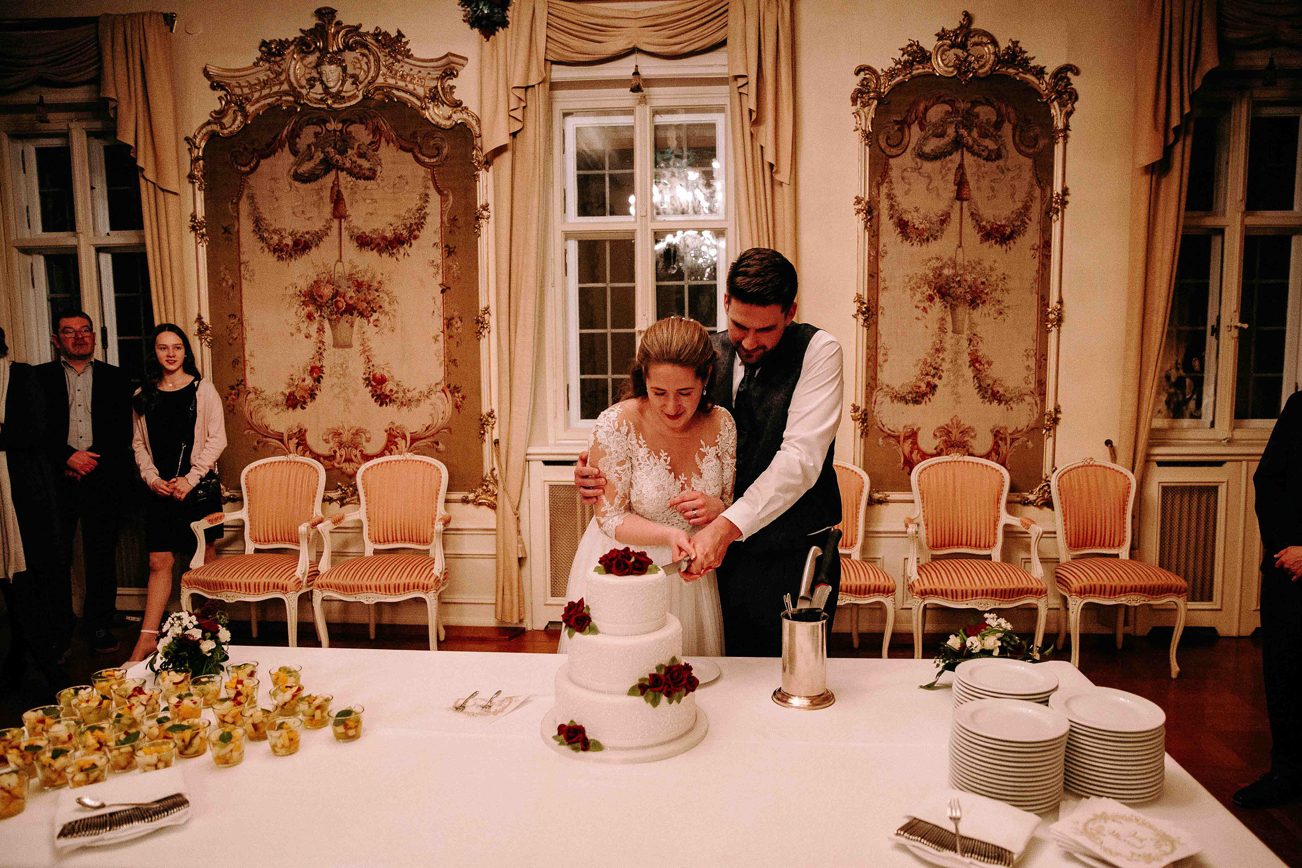 Braut und Bräutigam schneiden gemeinsam die Hochzeitstorte an im festlichen Saal