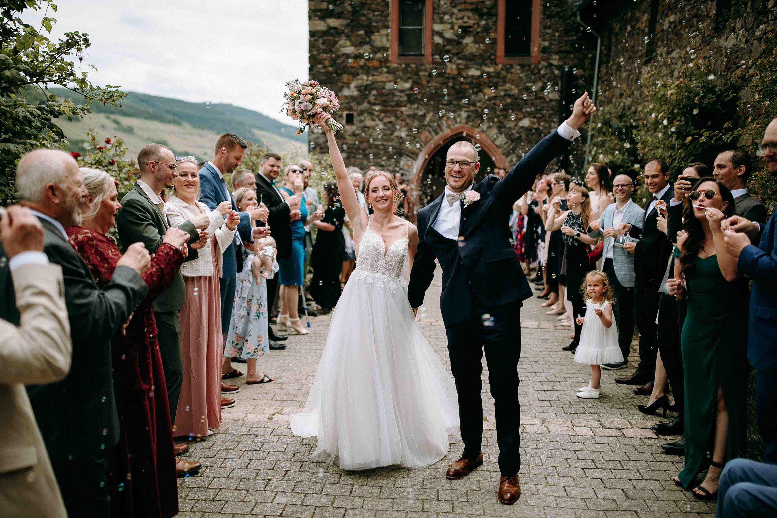 Hochzeitspaar wird auf Burg Reichenstein von Gästen mit Seifenblasen begrüßt – Hochzeitsfotograf Rheingau