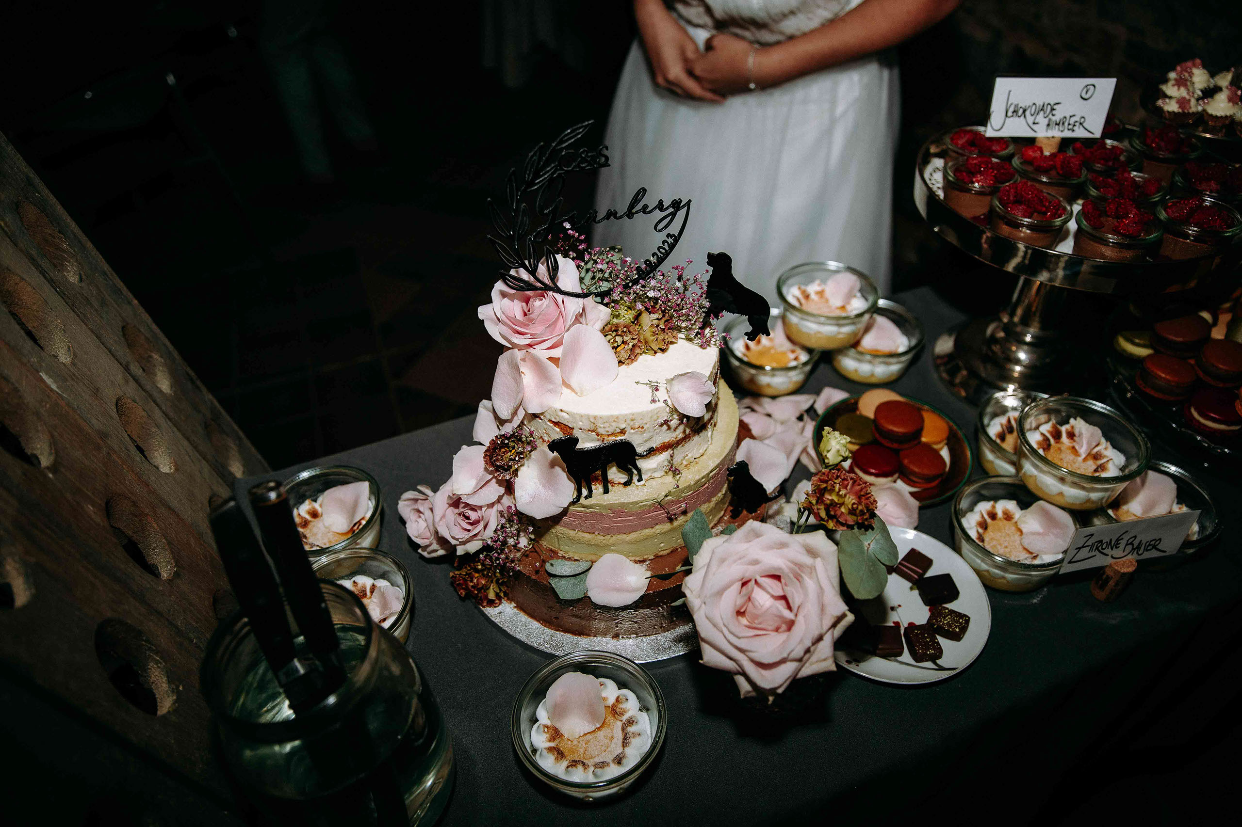 Detailaufnahme der liebevoll dekorierten Hochzeitstorte mit Rosen, Trockenblumen und Hunde-Topper – Weingut Georg Breuer