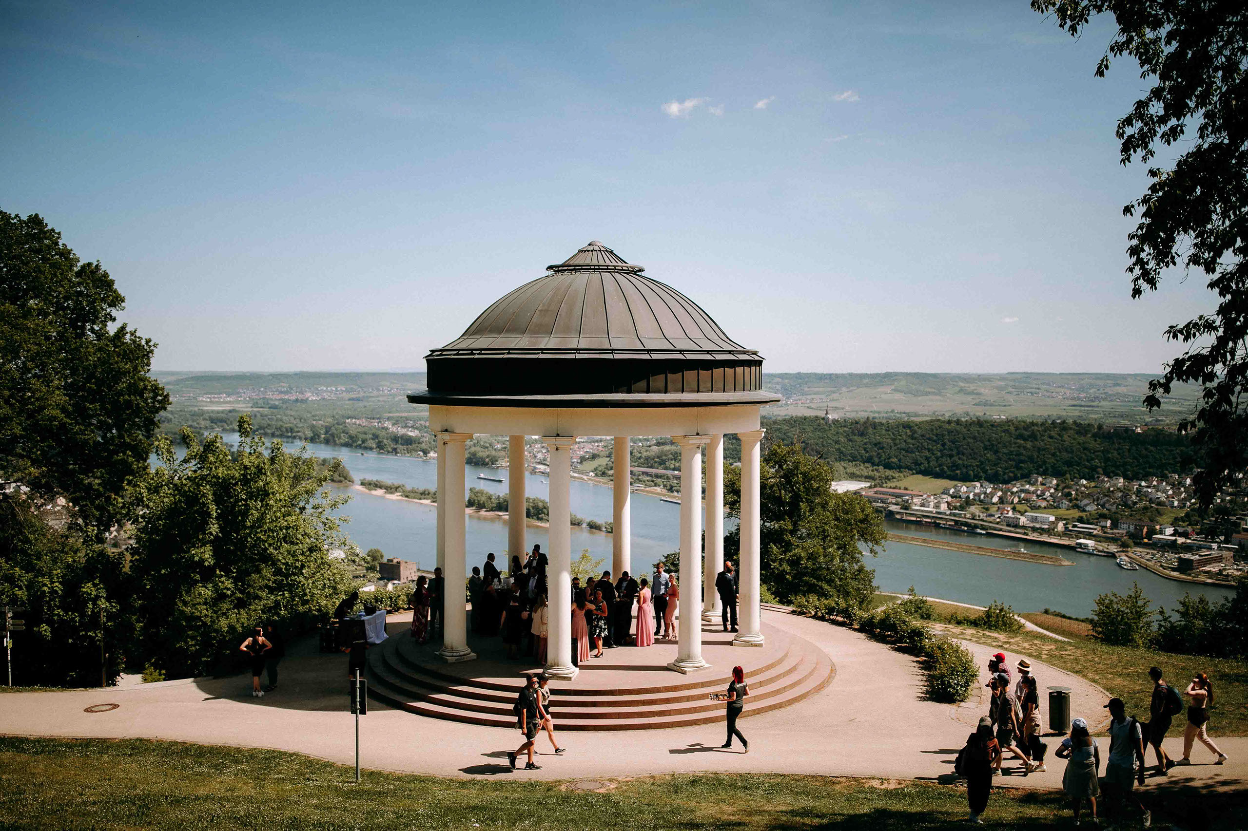 Gäste feiern unter dem Niederwaldtempel mit Blick über den Rhein – Hochzeitslocation im Rheingau.