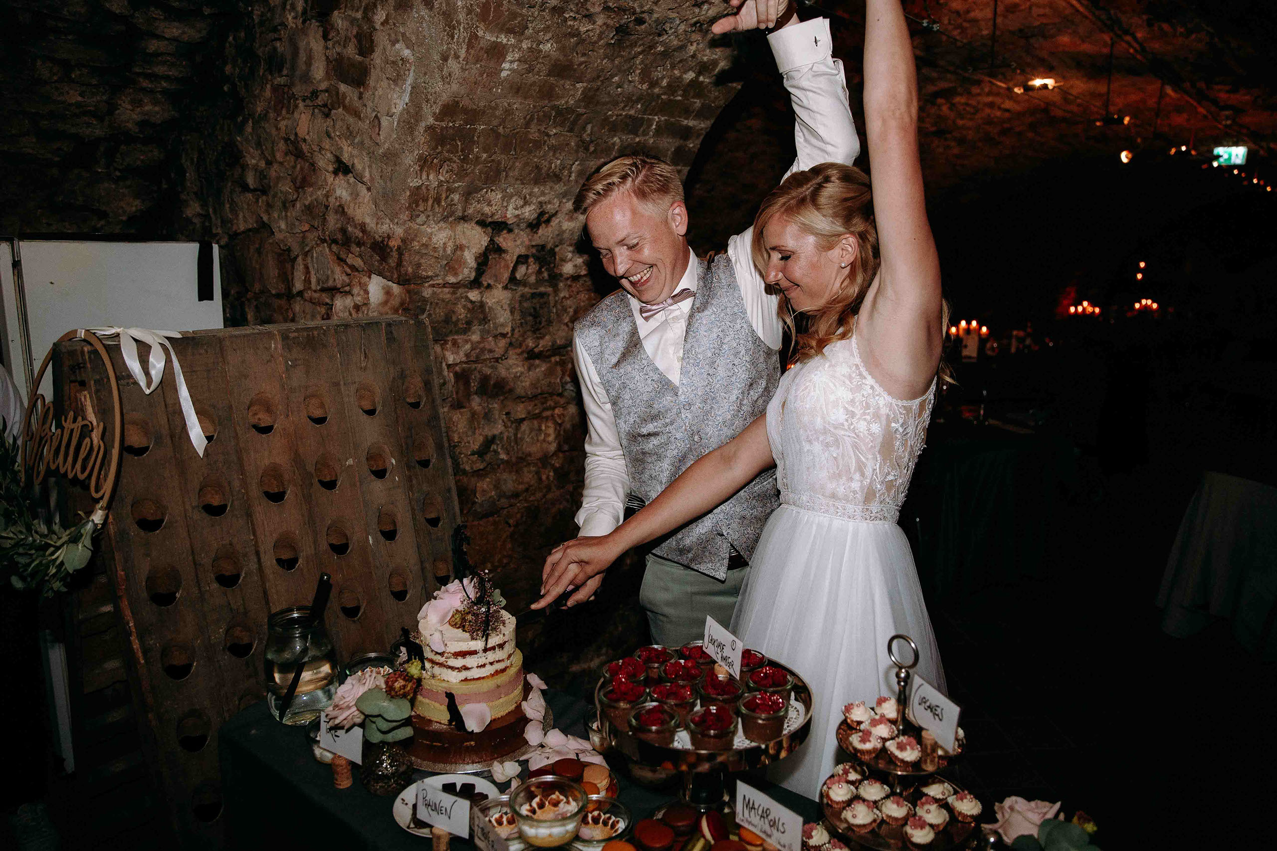 Das Brautpaar feiert ausgelassen den Tortenanschnitt im stilvollen Weinkeller des Weinguts Georg Breuer