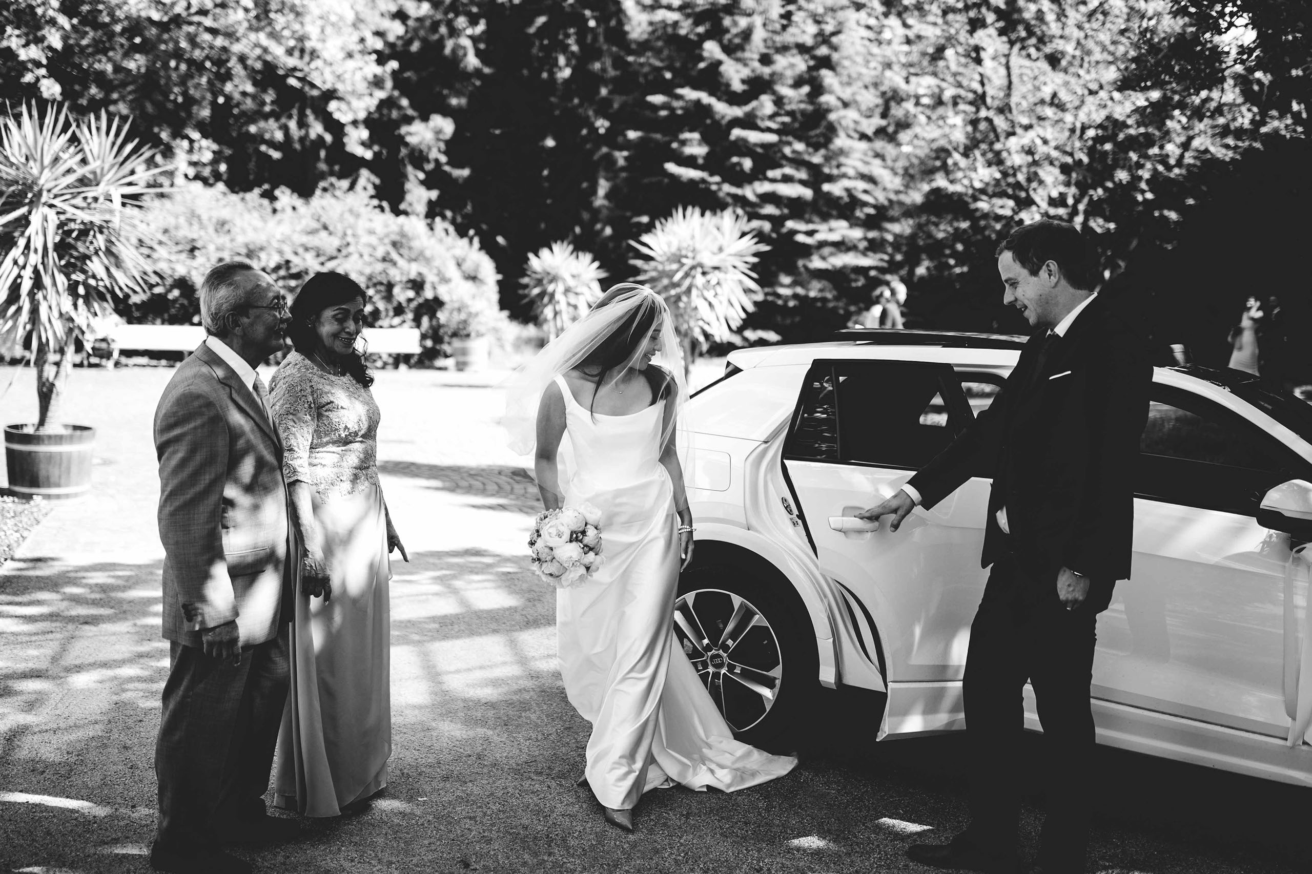 Braut steigt aus weißem Auto bei ihrer Ankunft zur Hochzeit in Bad Homburg – Schwarzweißfoto.