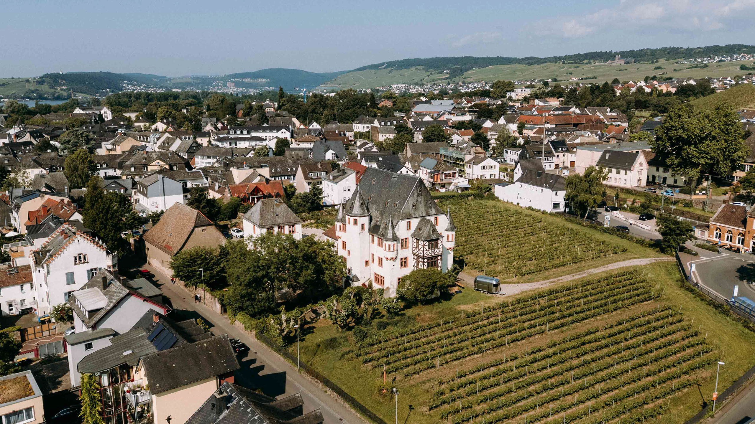 Drohnenaufnahme des Schlosses Schoenborn mit Blick auf die Stadt Geisenheim und umliegende Weinberge – Hochzeitsfotograf Rheingau