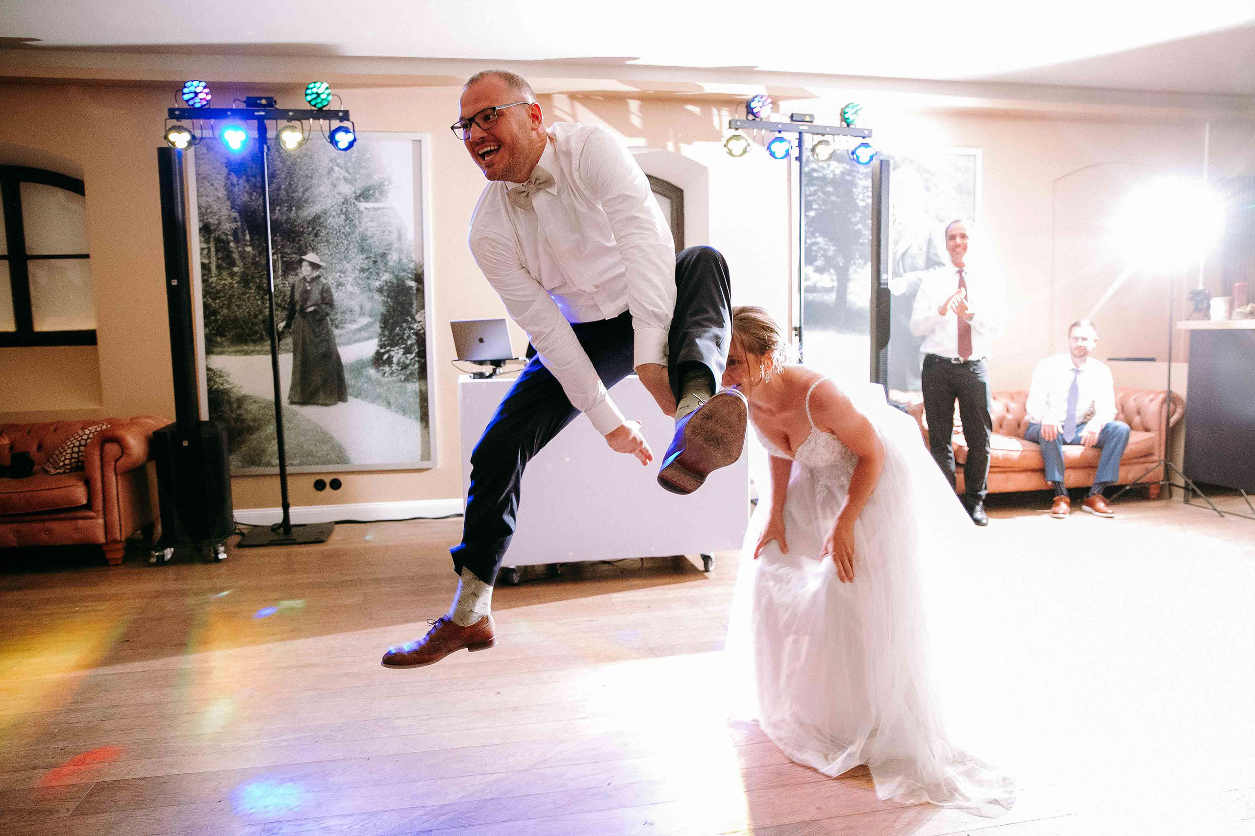 Hochzeitslocation Burg Reichenstein: Bräutigam springt mit Schwung bei der Feier über die Braut