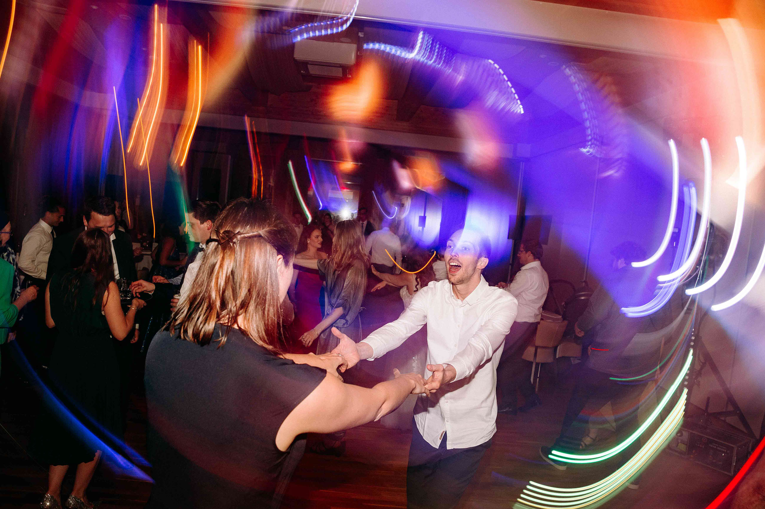 Gäste tanzen ausgelassen unter bunten Lichtern bei der Hochzeitsfeier im Taktgefühl Eventhaus Friedrichsdorf