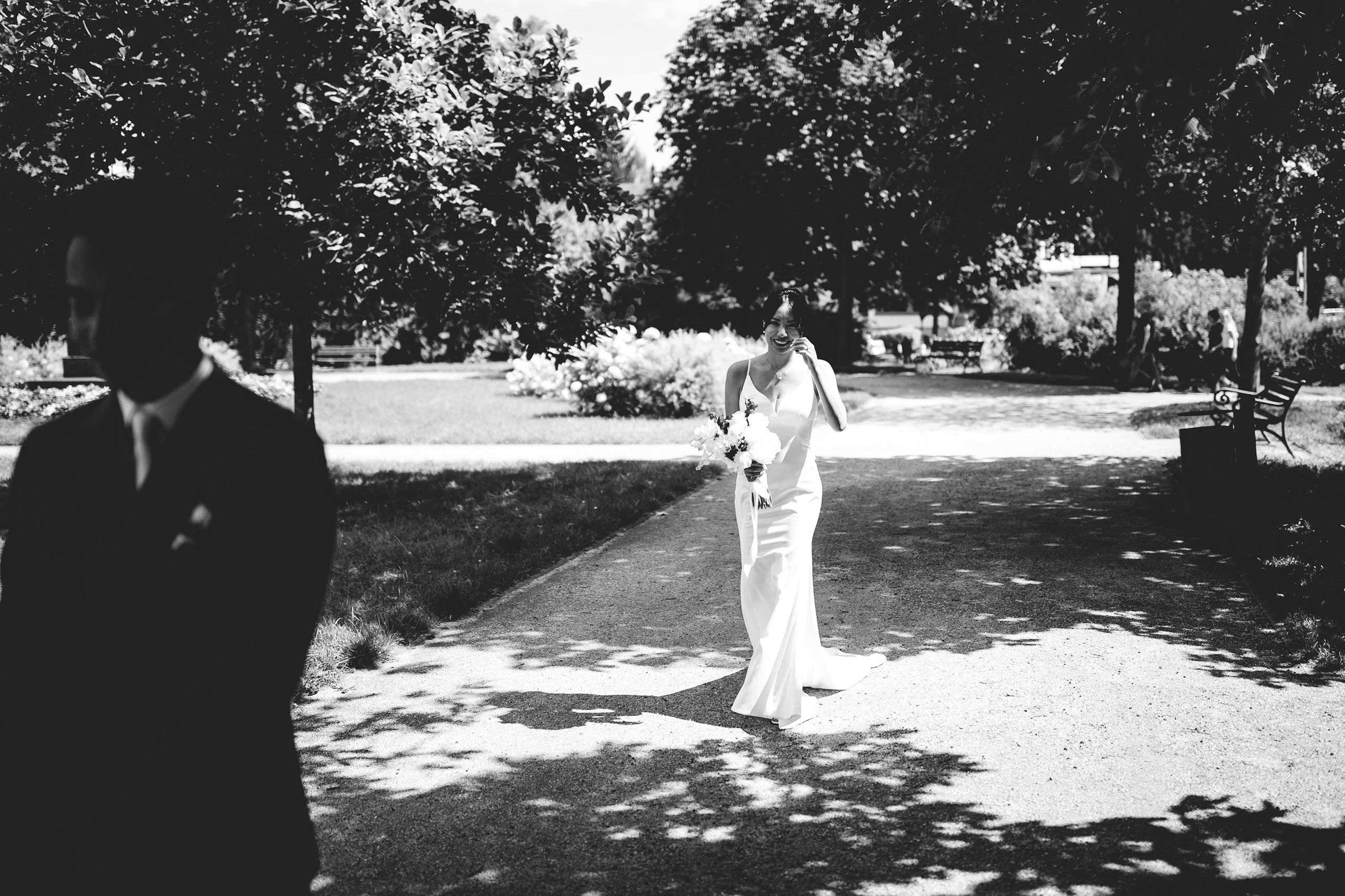 Braut nähert sich dem Bräutigam im Kurpark für den First Look