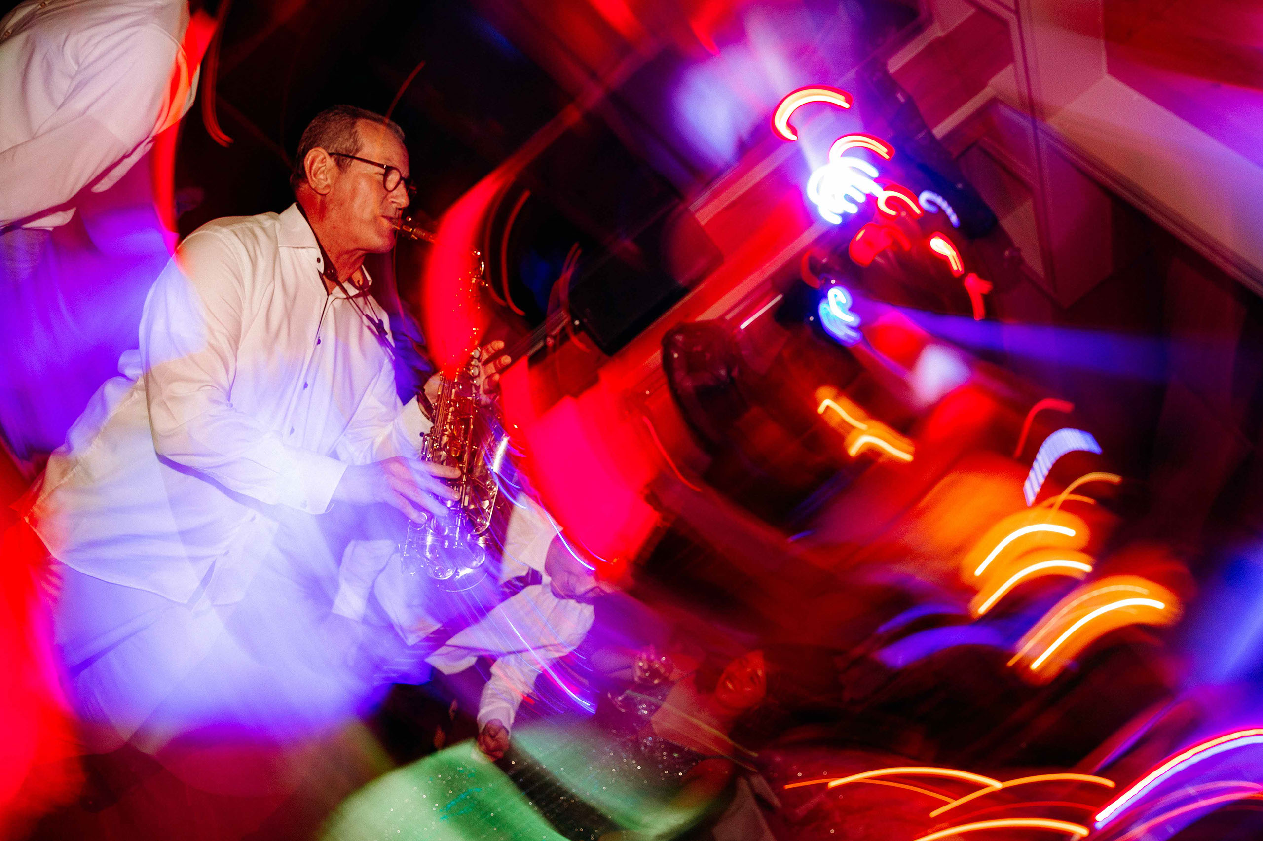 Ein Saxophonist performt unter bunten Lichtern bei der Hochzeitsfeier im Taktgefühl Eventhaus Friedrichsdorf