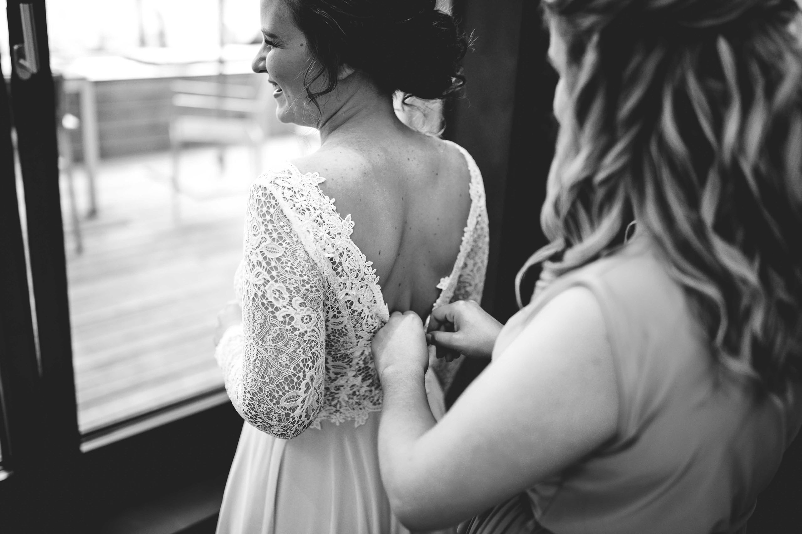 Die Braut wird beim Schließen ihres Spitzenkleides unterstützt – Hochzeitsfotograf Burg Schwarzenstein