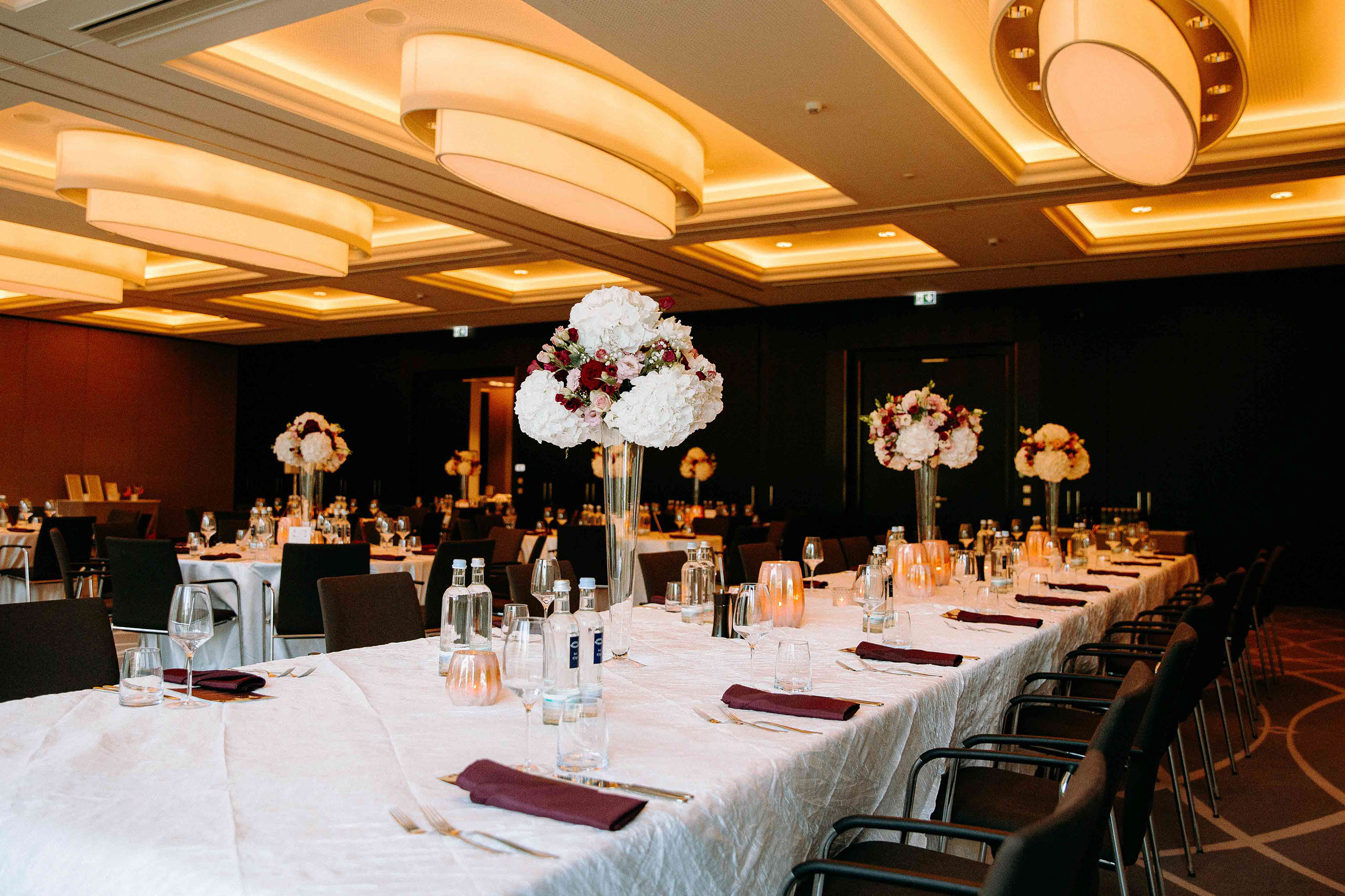 Große weiße Blumengestecke auf langen Tischen – Hochzeitsfeier im Dorint Hotel Oberursel.