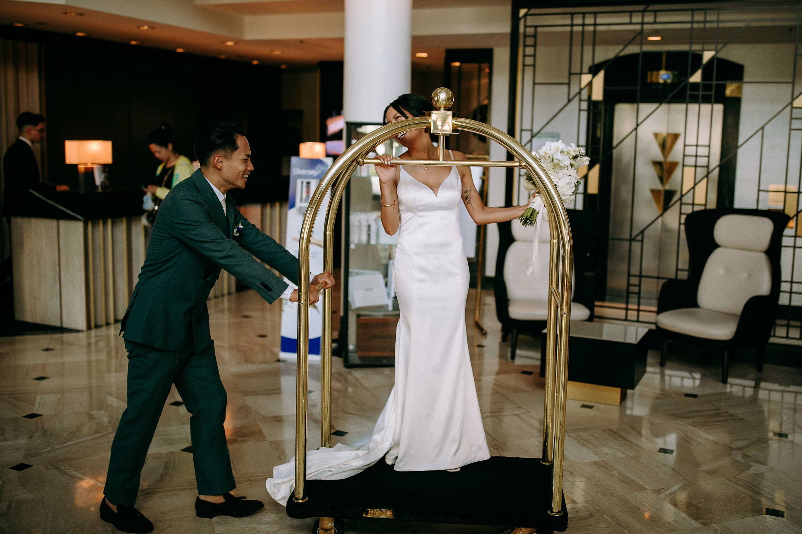 Braut auf Gepäckwagen in der Hotellobby – lustiger Hochzeitsmoment