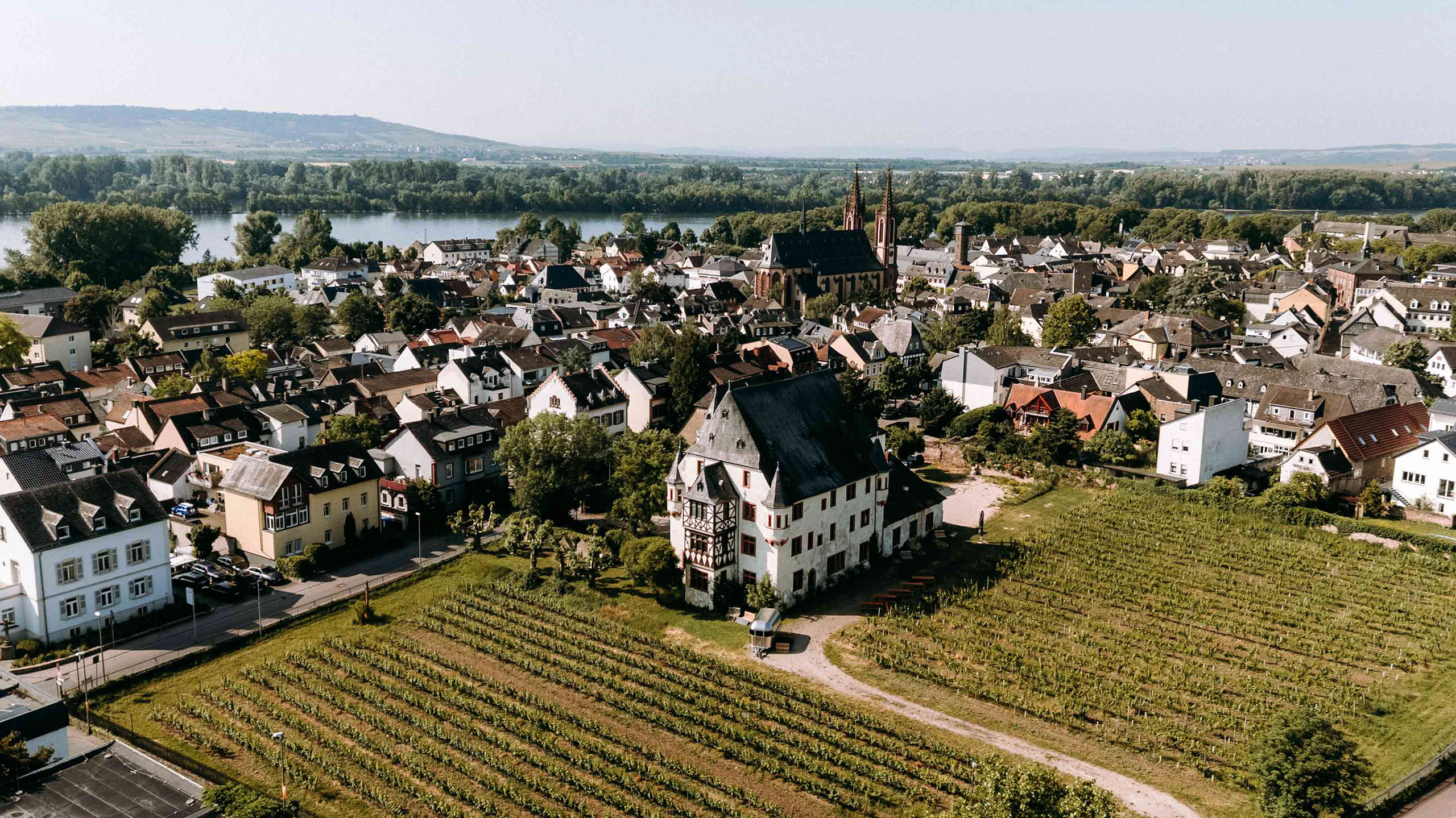 Weitwinkel-Drohnenbild vom Schloss Schoenborn mit Rheinpanorama im Hintergrund – fotografiert vom Hochzeitsfotografen aus dem Rheingau 
