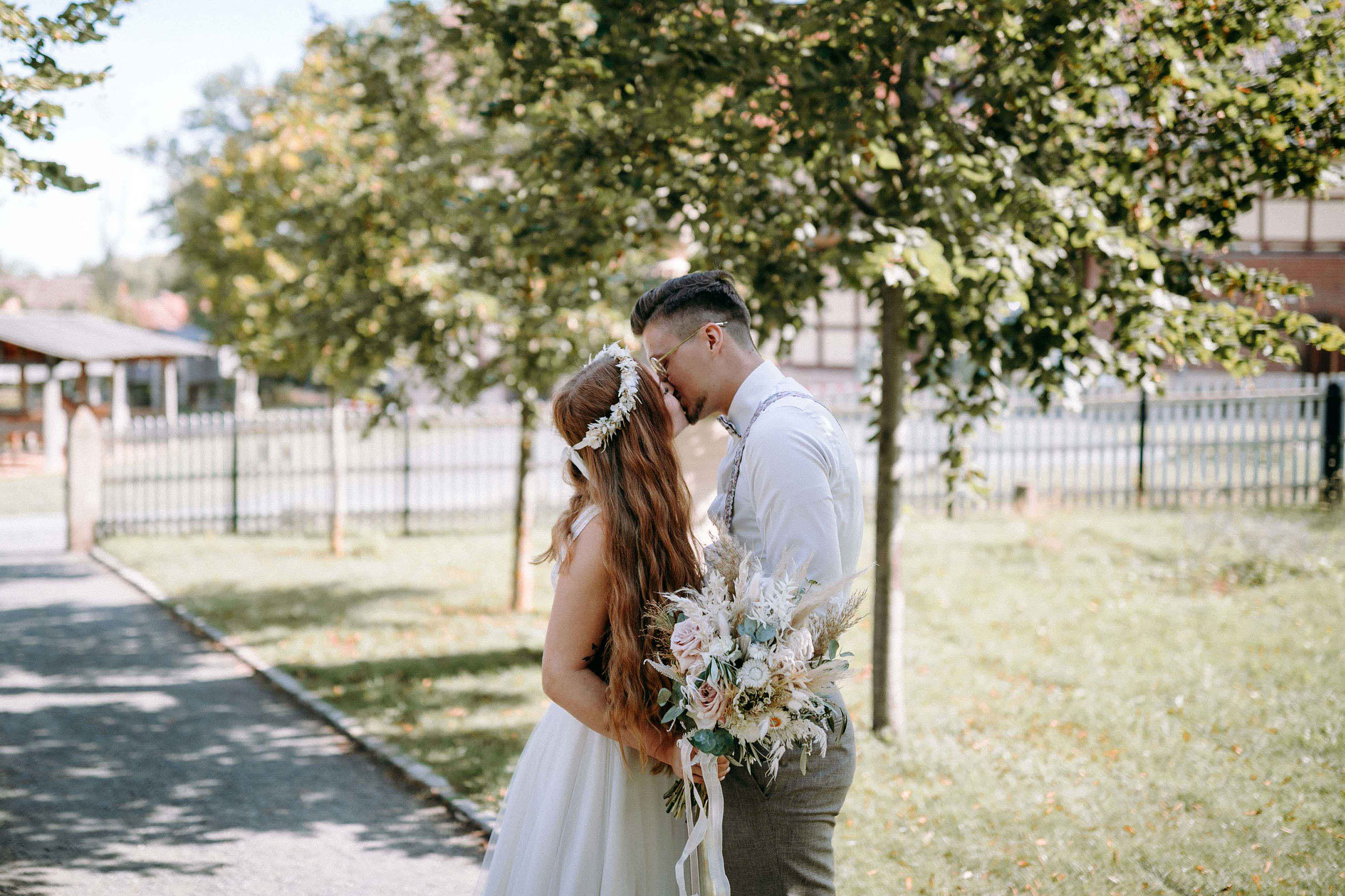 Romantischer Kuss eines Brautpaars unter Bäumen im Freilichtmuseum Hessenpark – Hochzeitsfotograf Bad Homburg.