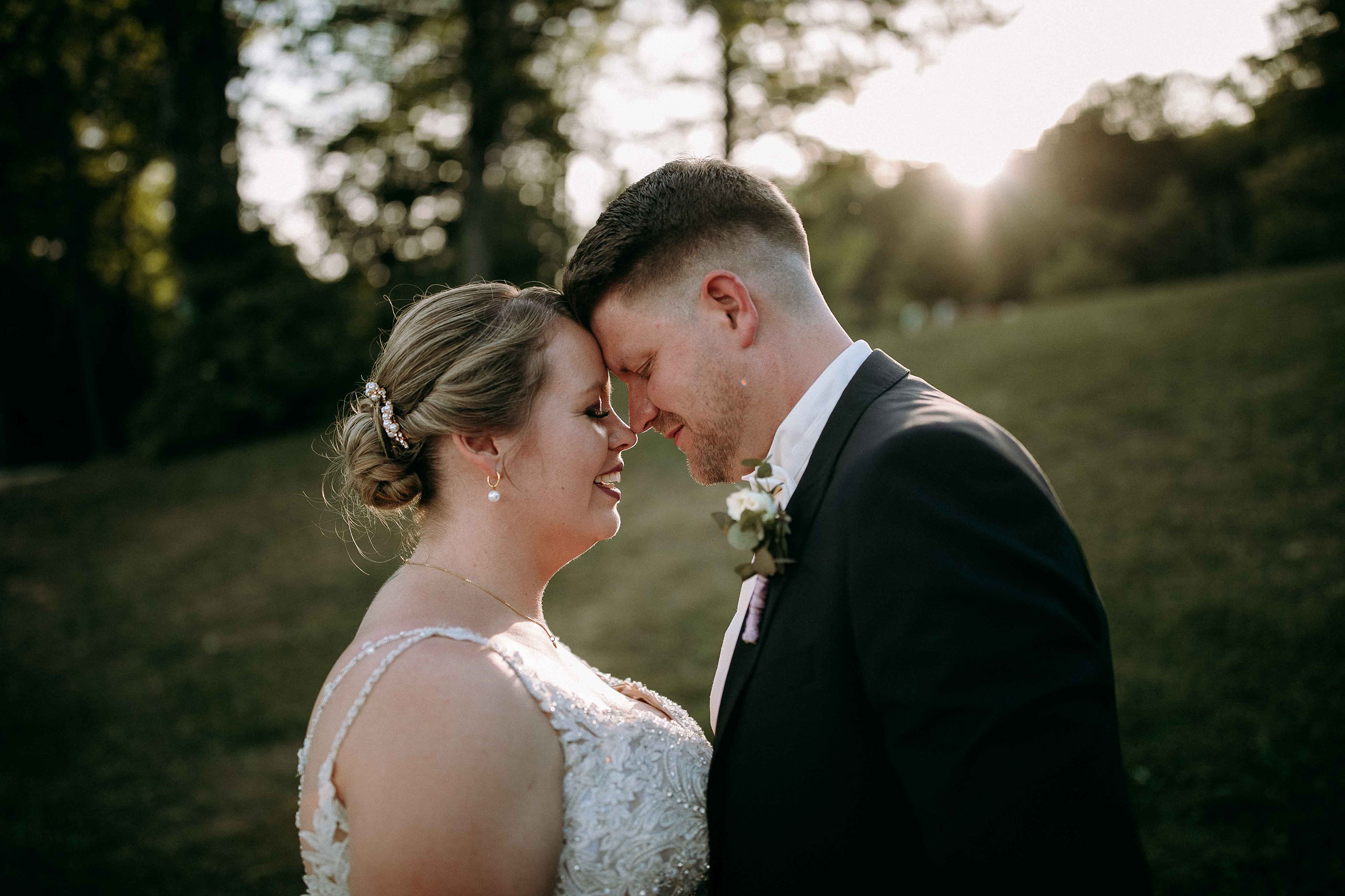 Braut und Bräutigam berühren sich liebevoll an der Stirn bei Sonnenuntergang in der Hochzeitslocation Am Niederwald.