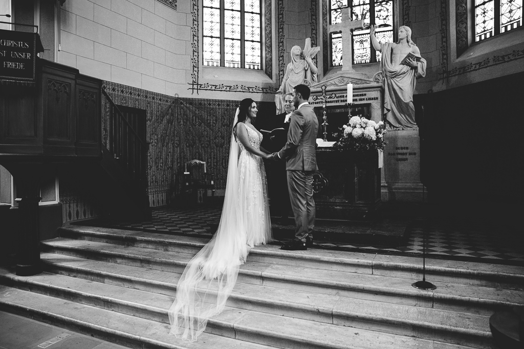 Das Brautpaar sieht sich verliebt im Kaiserdom am Altar an.