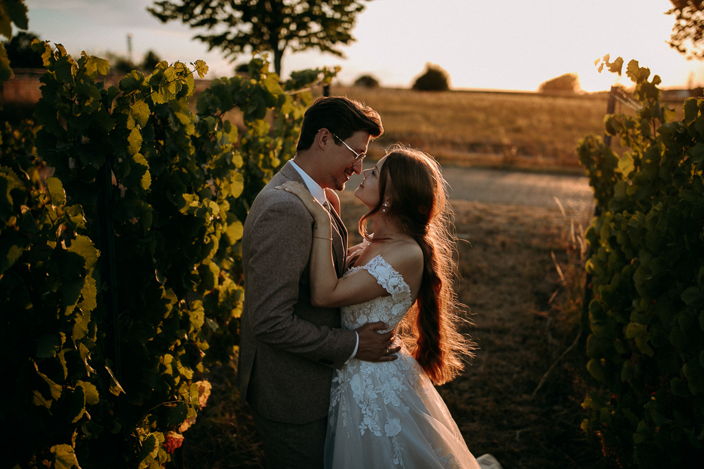 Das Brautpaar steht vor dem offenen Fenster und schaut sich an.