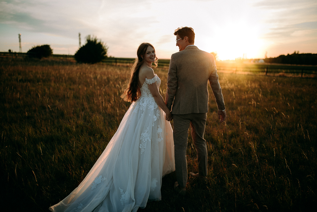 Das Brautpaar steht vor dem offenen Fenster und schaut sich an.