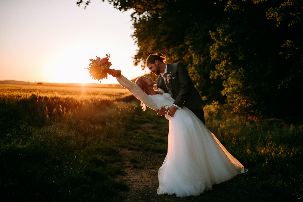 Das Brautpaar steht vor dem offenen Fenster und schaut sich an.