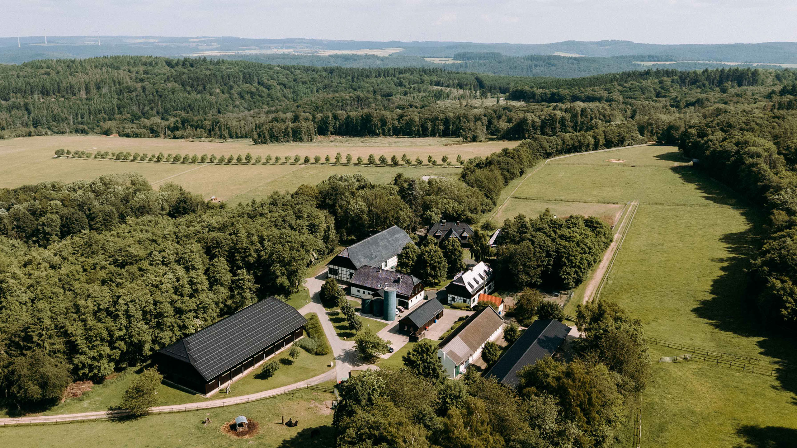 Weitläufige Luftaufnahme des Hofguts Mappen, umgeben von Wäldern, Wiesen und Reitwegen – abgeschiedene Hochzeitslocation im Grünen